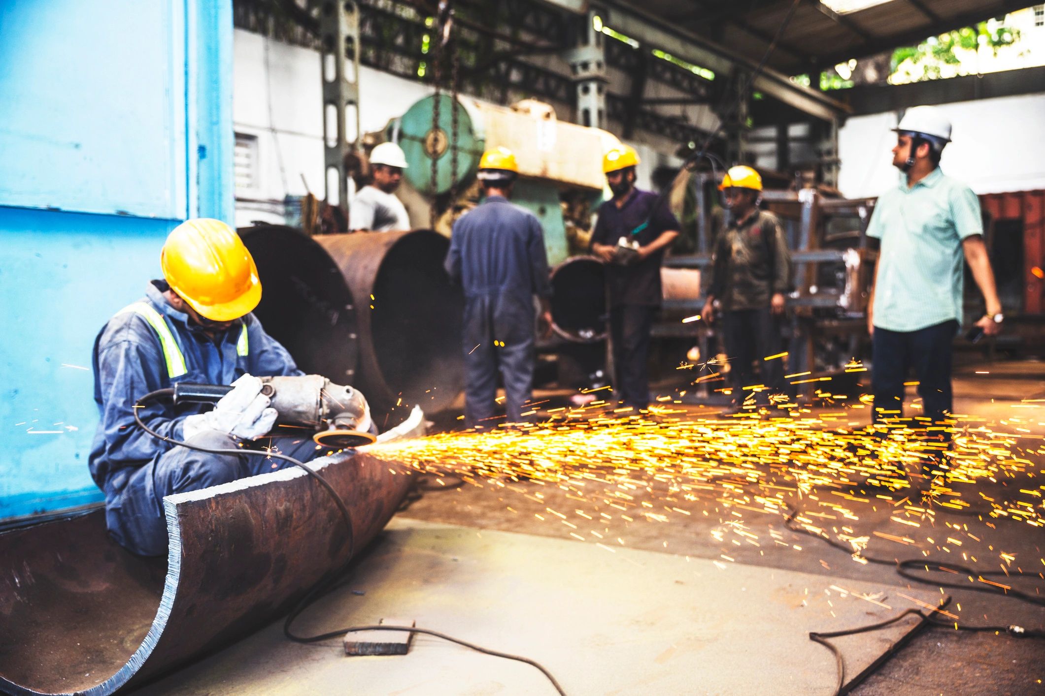 Metal grinder working on a large metal pipe in a workshop