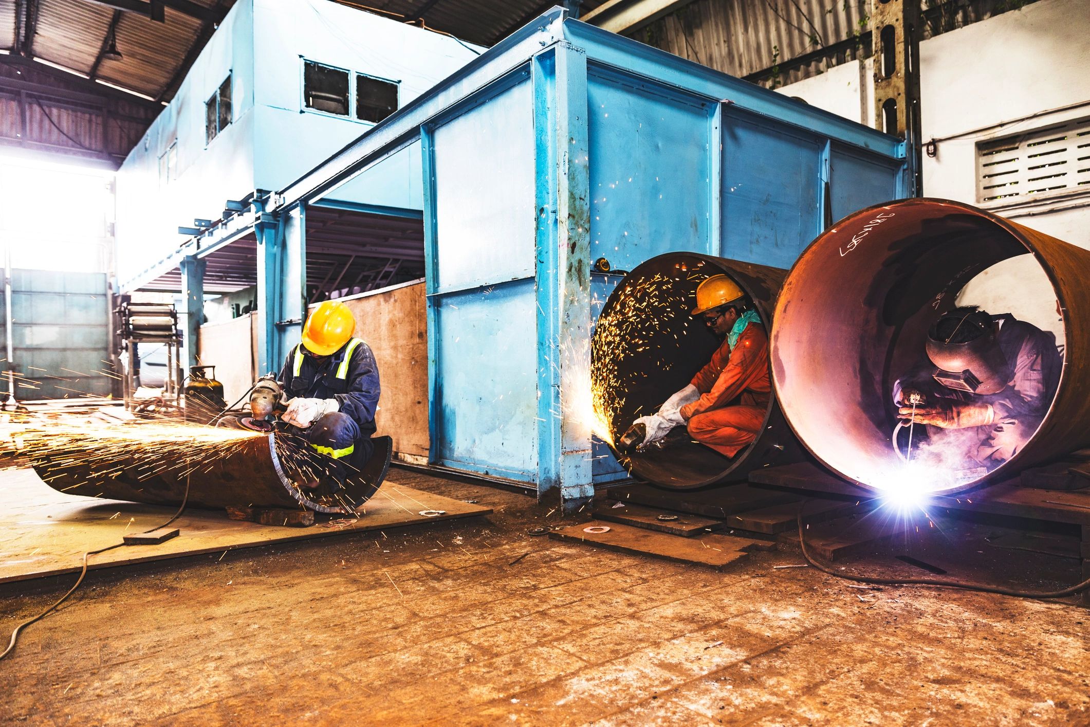 Factory crew welding and grinding metal